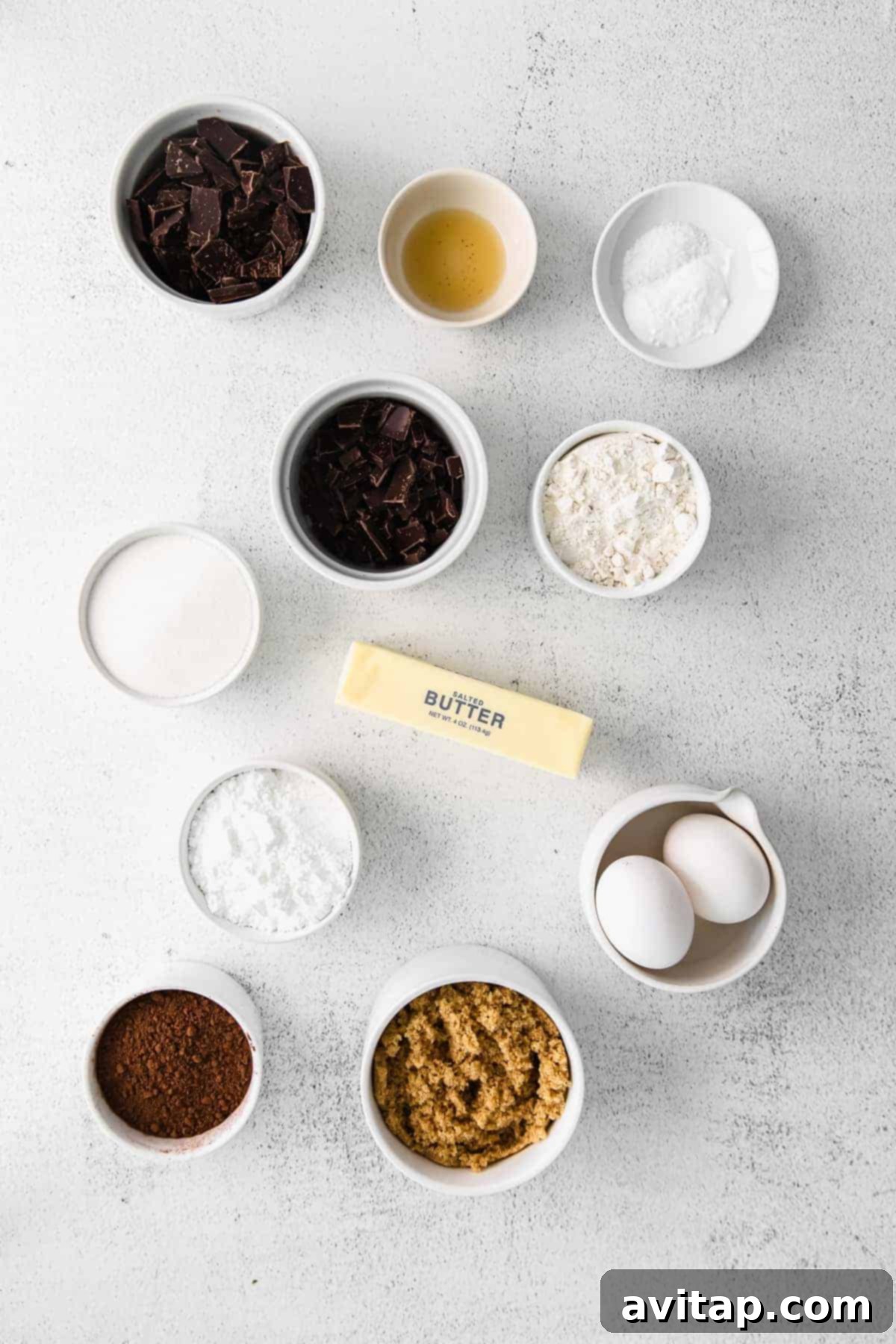 Key Ingredients for Delicious Chocolate Crinkle Cookies Assorted ingredients for chocolate crinkle cookies laid out on a clean kitchen countertop, including various types of chocolate, flour, sugar, and butter.