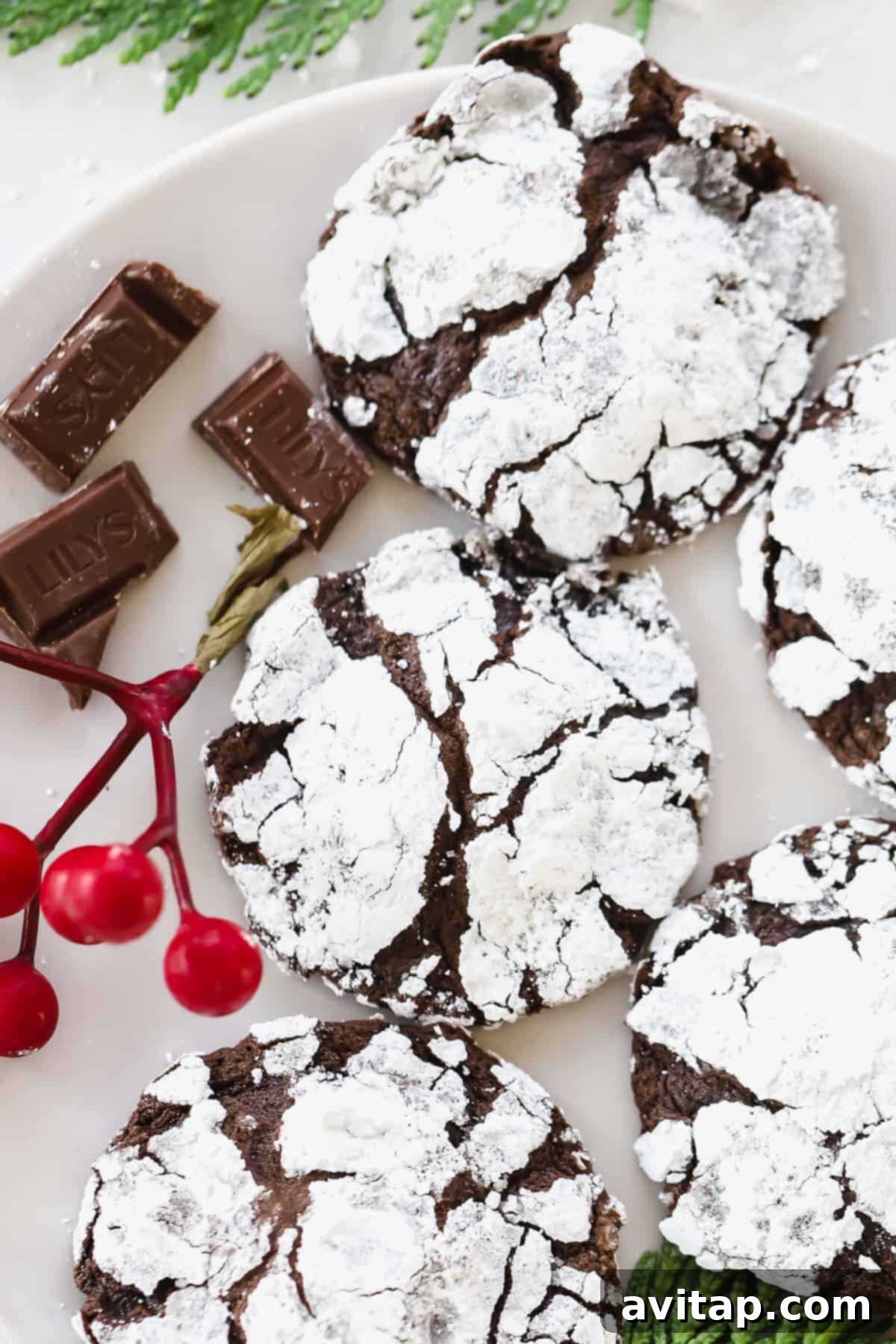 Delicious Stack of Chocolate Crinkle Cookies A stack of freshly baked chocolate crinkle cookies, perfectly crinkled and dusted with powdered sugar, arranged on a kitchen countertop.