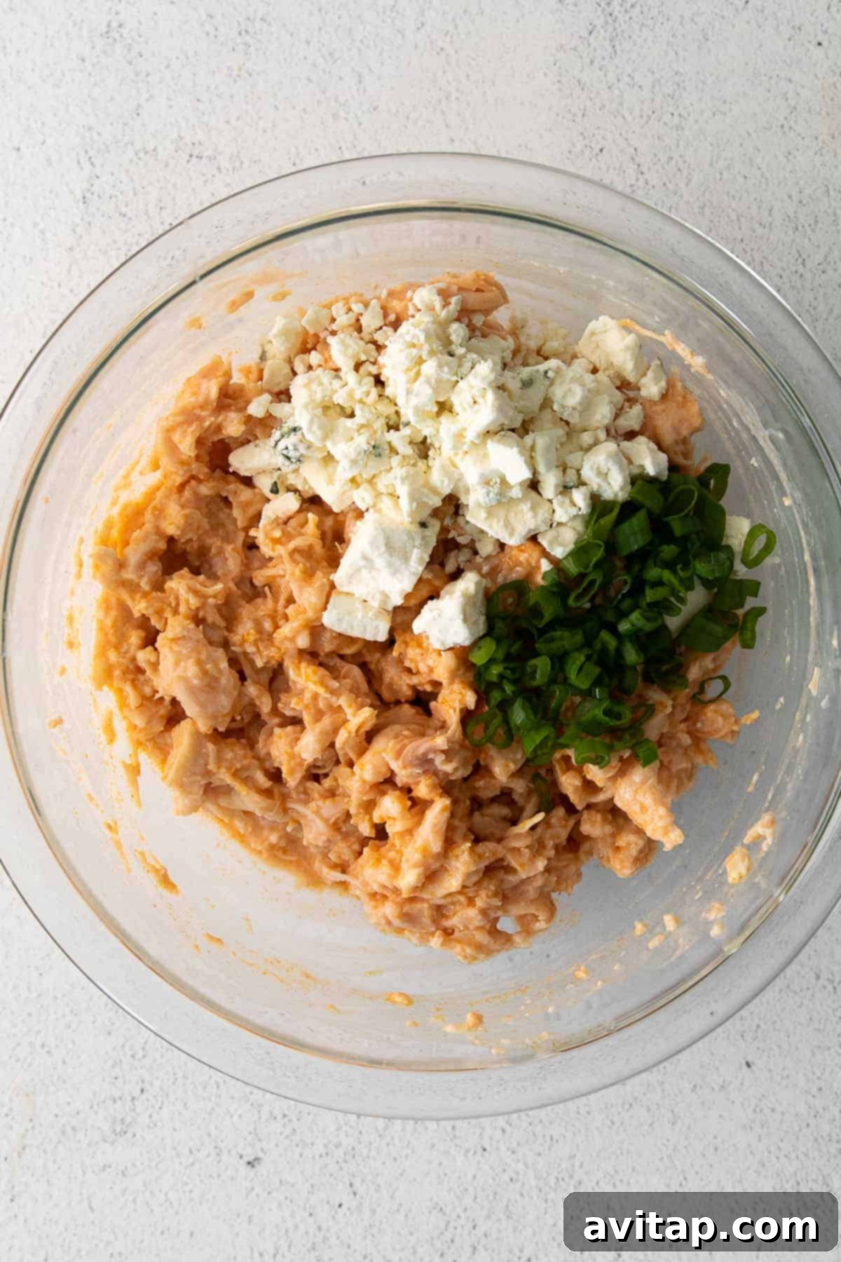 A bowl of shredded buffalo chicken filling, perfectly mixed and ready to be spooned into wonton wrappers.