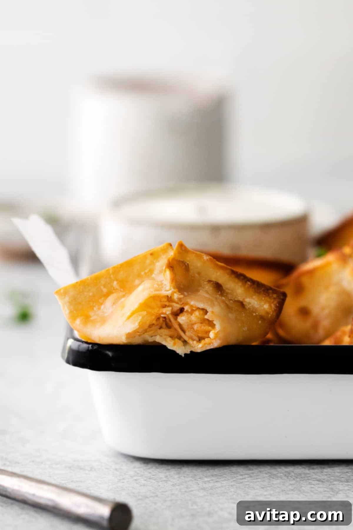 A basket full of golden-brown air-fried buffalo chicken wontons, showcasing their crispy texture.