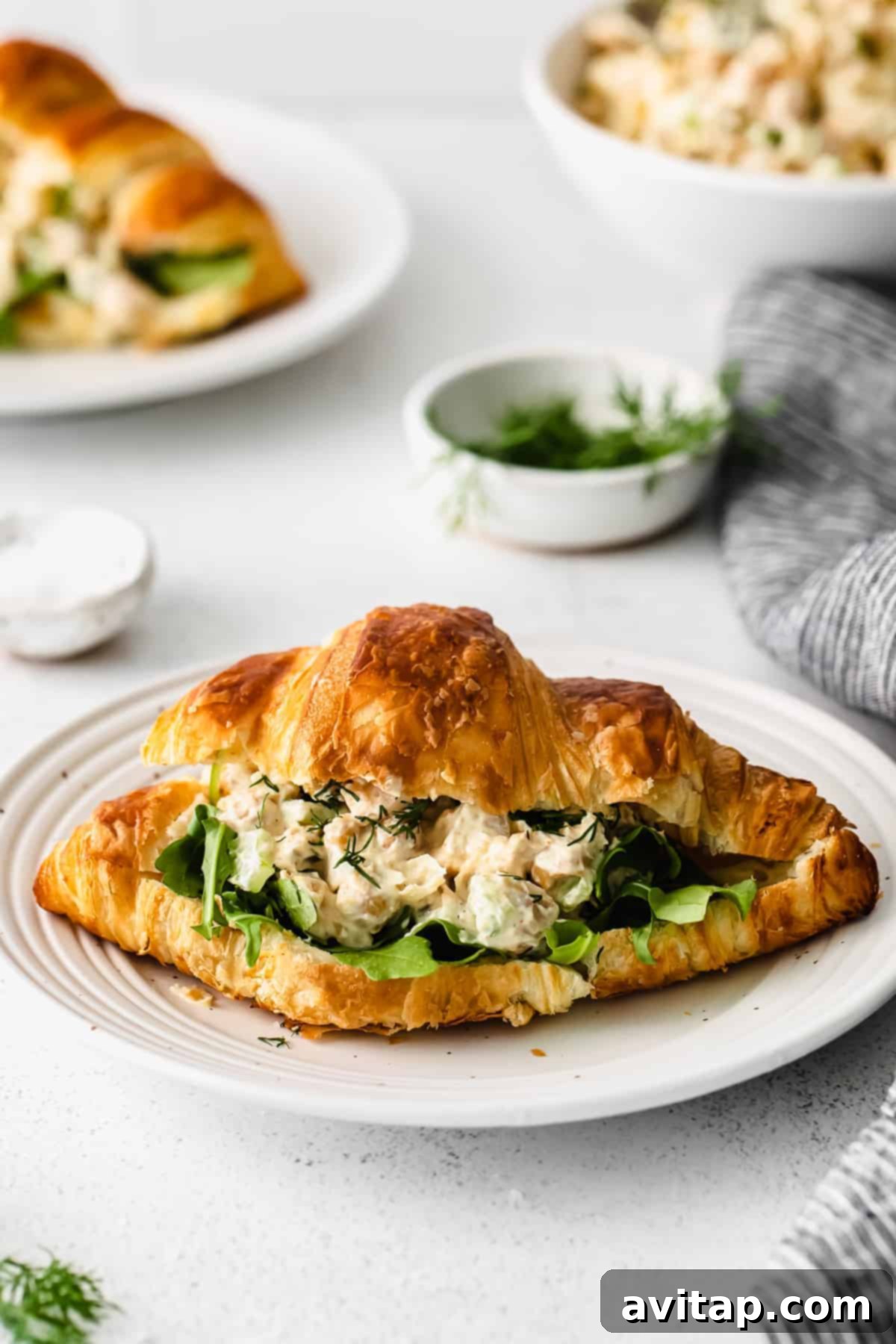 Delicious chickpea salad served on a flaky croissant, ready to be enjoyed as a plant-based sandwich, garnished with fresh herbs.