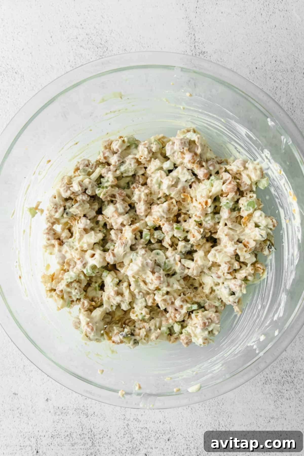 A large bowl of freshly made chickpea salad, generously garnished with fresh dill and a sprinkle of paprika, showcasing its vibrant colors and inviting creamy texture.