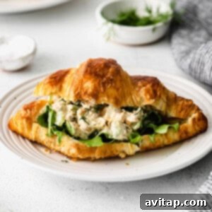 A delightful chickpea salad sandwich on a plate, featuring a golden croissant filled with creamy chickpea mixture, ready to be served.