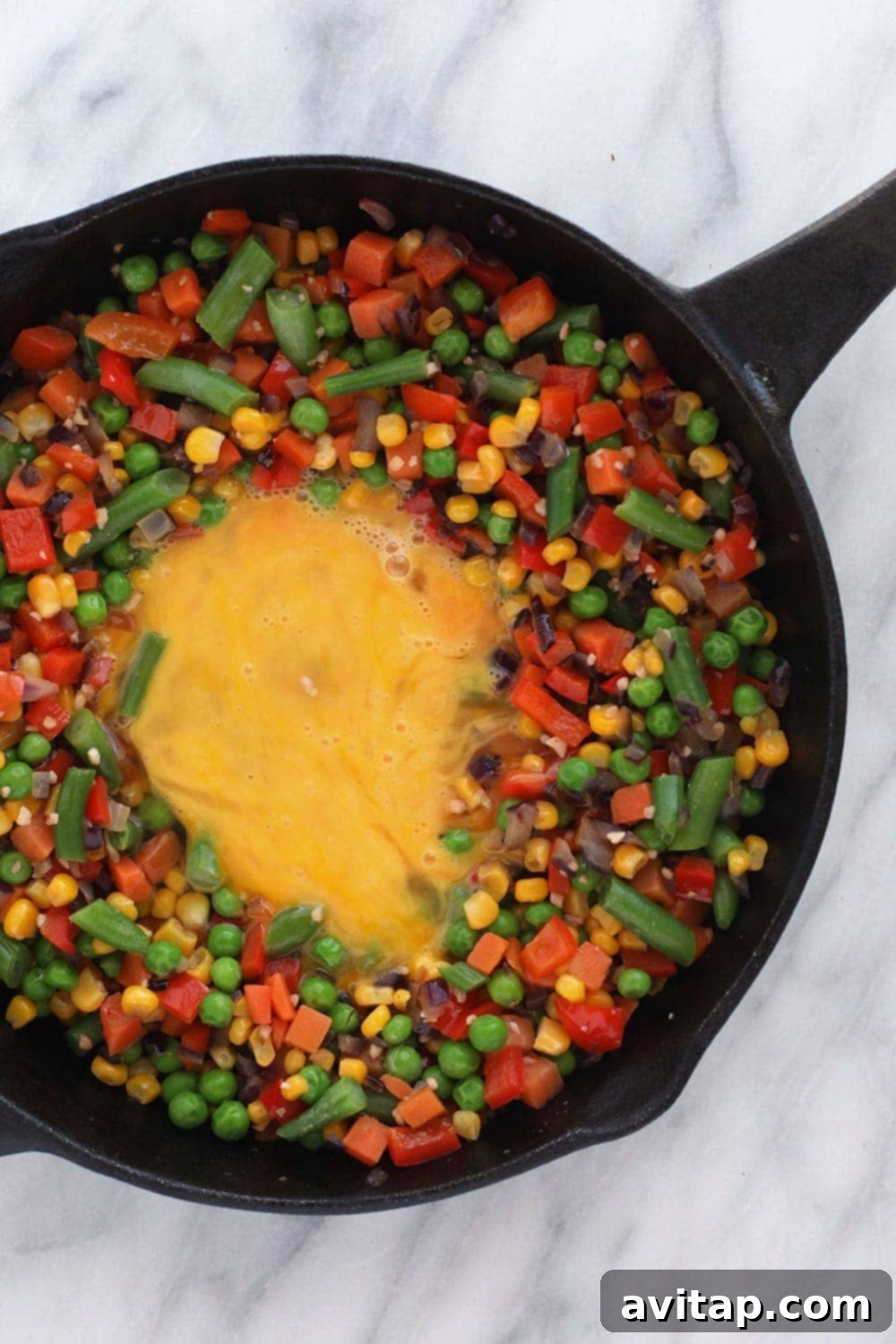 Chef scrambling eggs and vegetables in a pan, preparing a healthy fried rice meal.