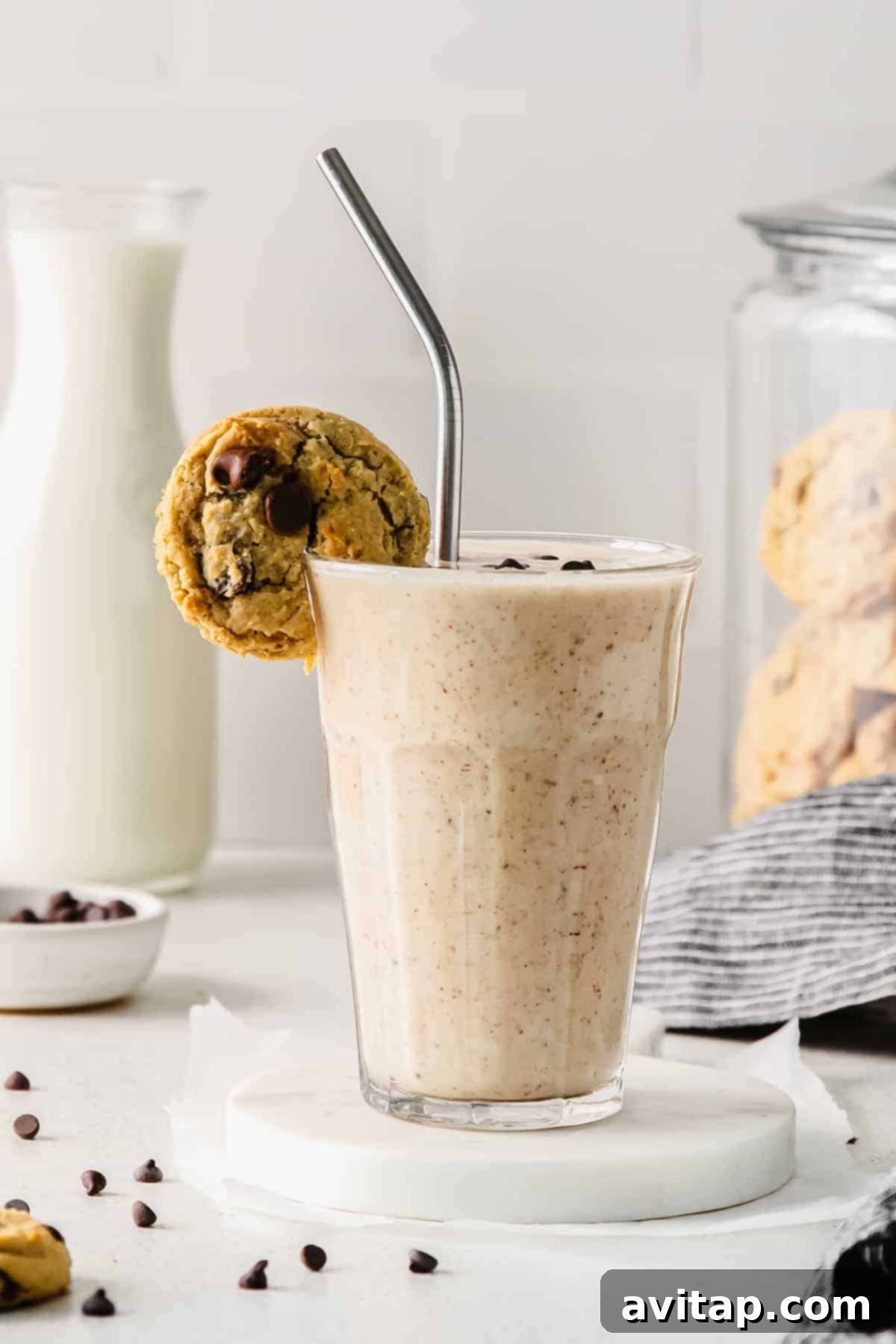 Decadent Chocolate Chip Cookie Dough Smoothie 7 A glass of chocolate chip cookie dough smoothie, topped with extra chocolate chips and a small cookie on the rim, showcasing its tempting texture.