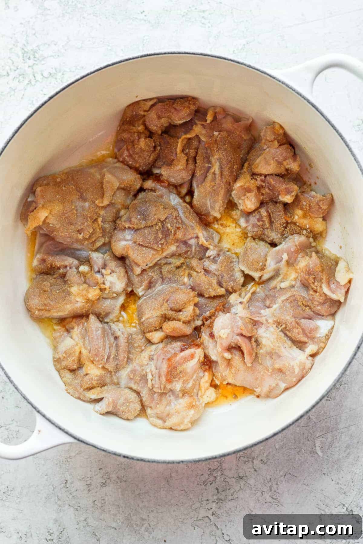 Close-up of boneless, skinless chicken thighs searing in ghee in a Dutch oven, achieving a perfect golden-brown crust