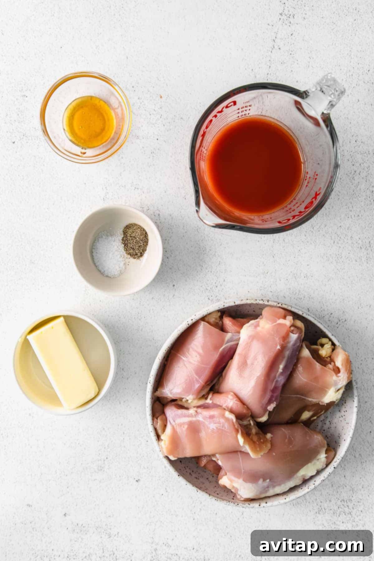 Ingredients for the Perfect Buffalo Chicken Thighs ingredients for baked boneless chicken thighs laid out on a wooden surface