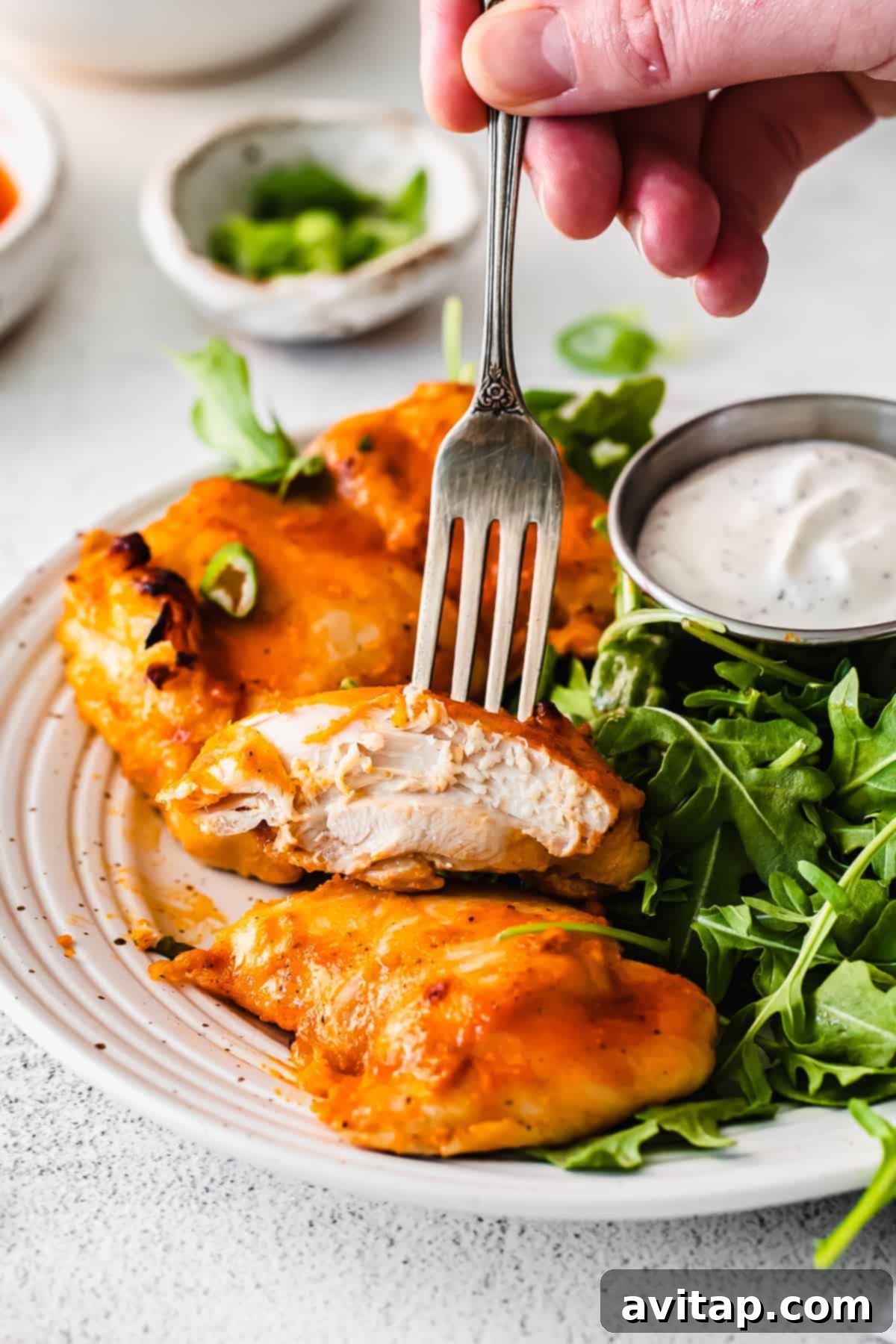 A Bite of Perfect Boneless Chicken Thigh a single boneless chicken thigh, perfectly cooked and glistening, held on a fork