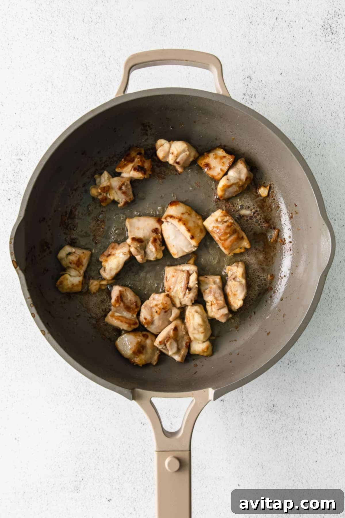 Chicken thighs browning in a skillet pan, creating rich, caramelized bits.