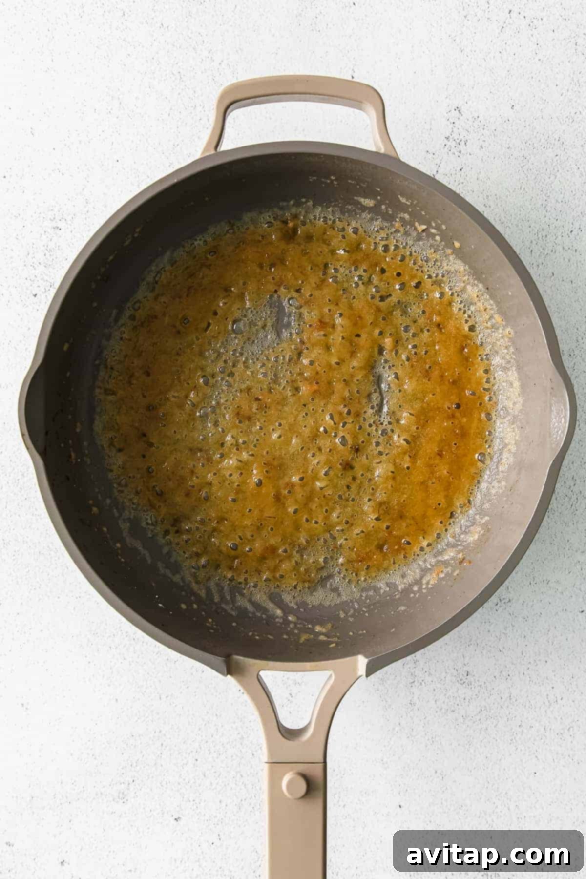 A pat of butter and a spoonful of flour in a skillet pan, forming the beginnings of a rich roux for alfredo sauce.