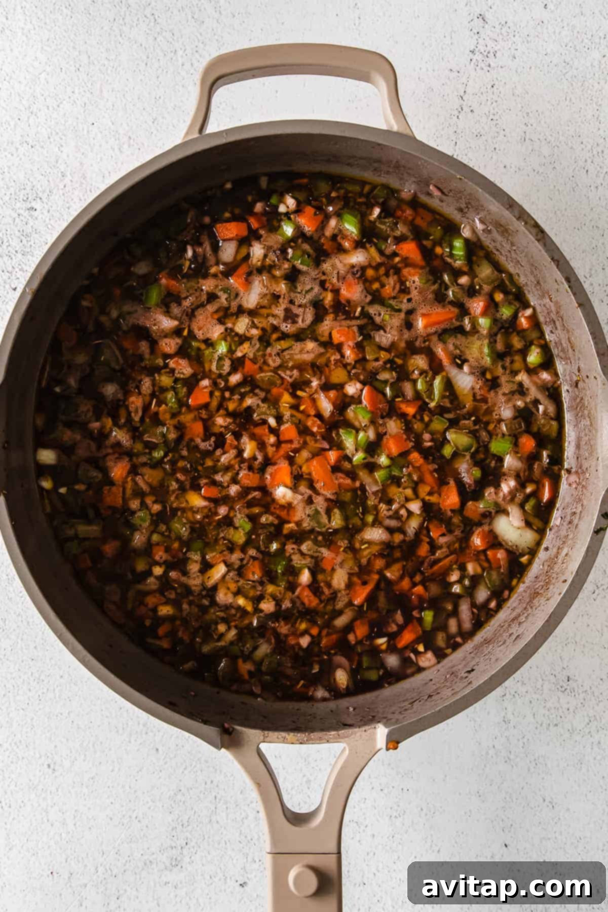 Sautéed Vegetables for Slow Cooker Bolognese Finely minced onions, garlic, celery, and carrots sautéing in a skillet, creating an aromatic base for the bolognese.