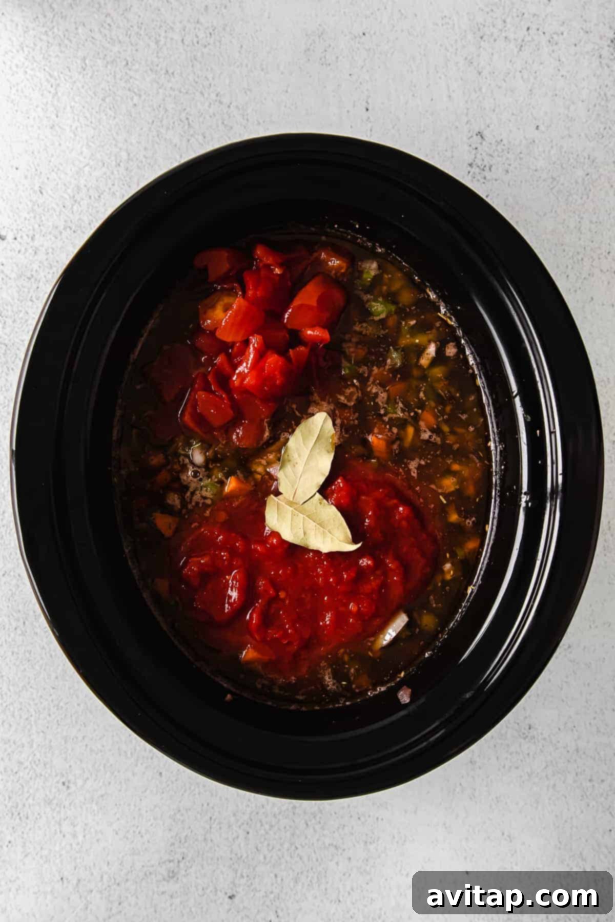 Ingredients Combined in the Slow Cooker All the slow cooker bolognese ingredients, including meats, vegetables, and tomatoes, combined in the slow cooker and ready to cook.