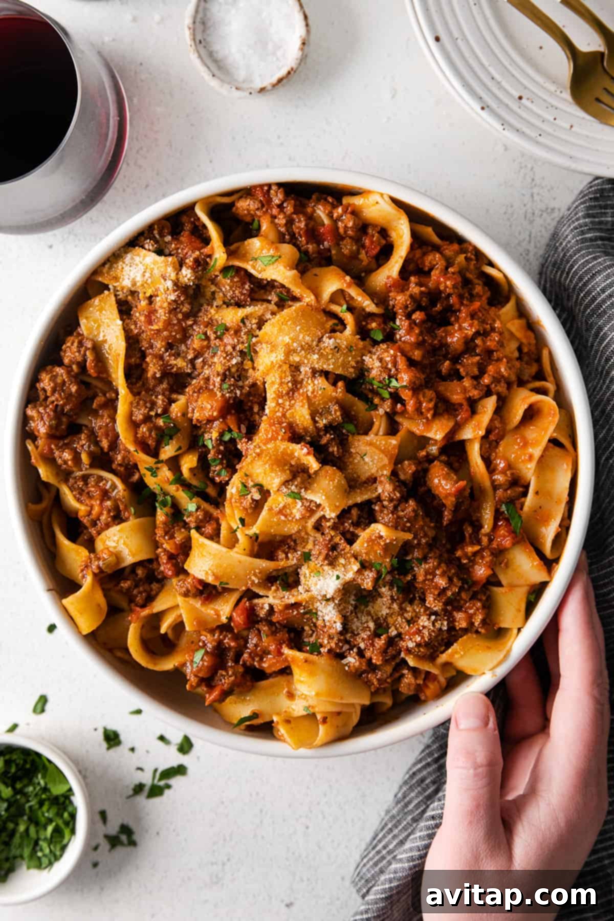 Bolognese with Pasta Ready to Serve A bowl of slow cooker bolognese with fresh pasta, garnished with herbs and ready for serving.