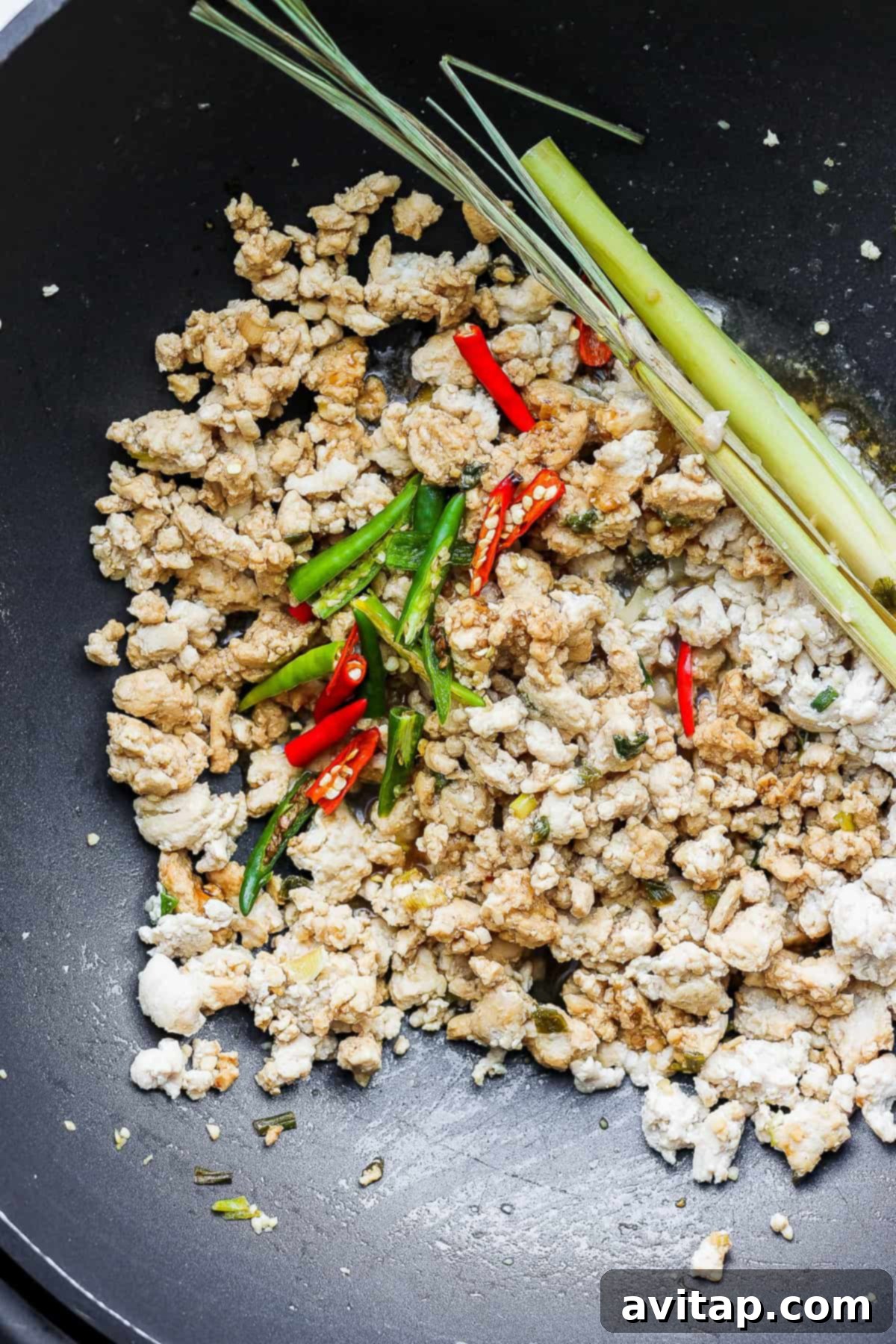 Finished Ground Chicken with Chili Peppers and Basil in a Wok Succulent cooked ground chicken stirred with vibrant green Thai chili peppers and fresh Thai basil in a large wok, capturing the essence of the stir-fry.