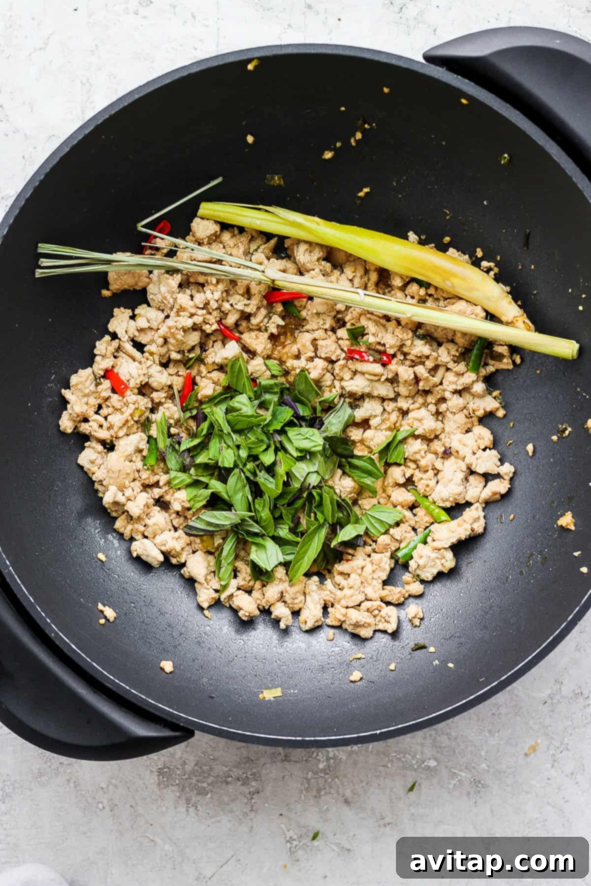 Cooking Thai Basil Chicken Stir Fry in a Wok A large wok filled with freshly cooked Thai Basil Chicken Stir Fry, vibrant with green basil leaves and red chili, steaming hot and ready to be served.