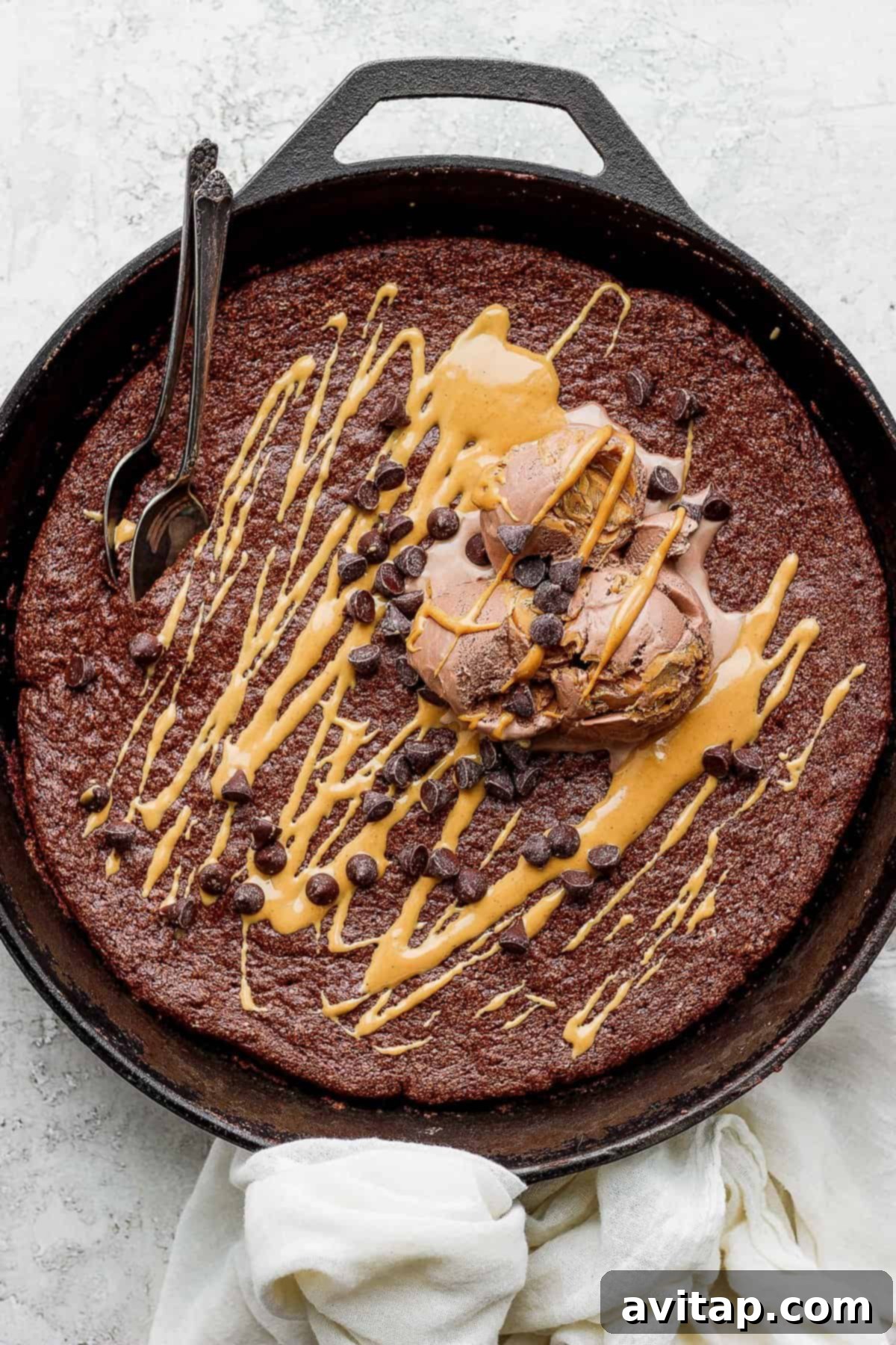Flourless Chocolate Skillet Cake with Toppings A beautifully baked flourless chocolate skillet cake, generously topped with a scoop of melting ice cream and a scattering of mini chocolate chips, ready for a spoon.