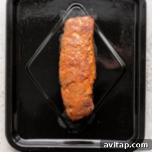 Seasoned pork tenderloin placed in an air fryer basket, ready for cooking.