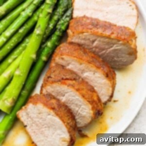 Air fryer pork tenderloin and asparagus beautifully arranged on a white plate, showcasing the recipe's delicious outcome.