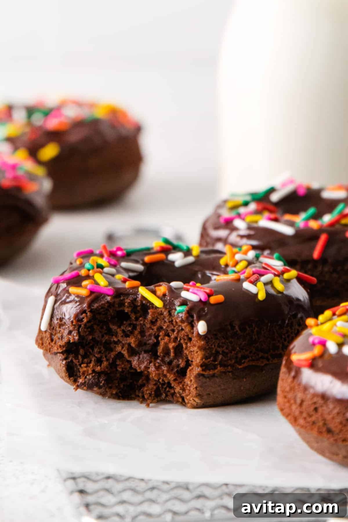 A chocolate baked donut with a bite taken out, revealing its moist interior.