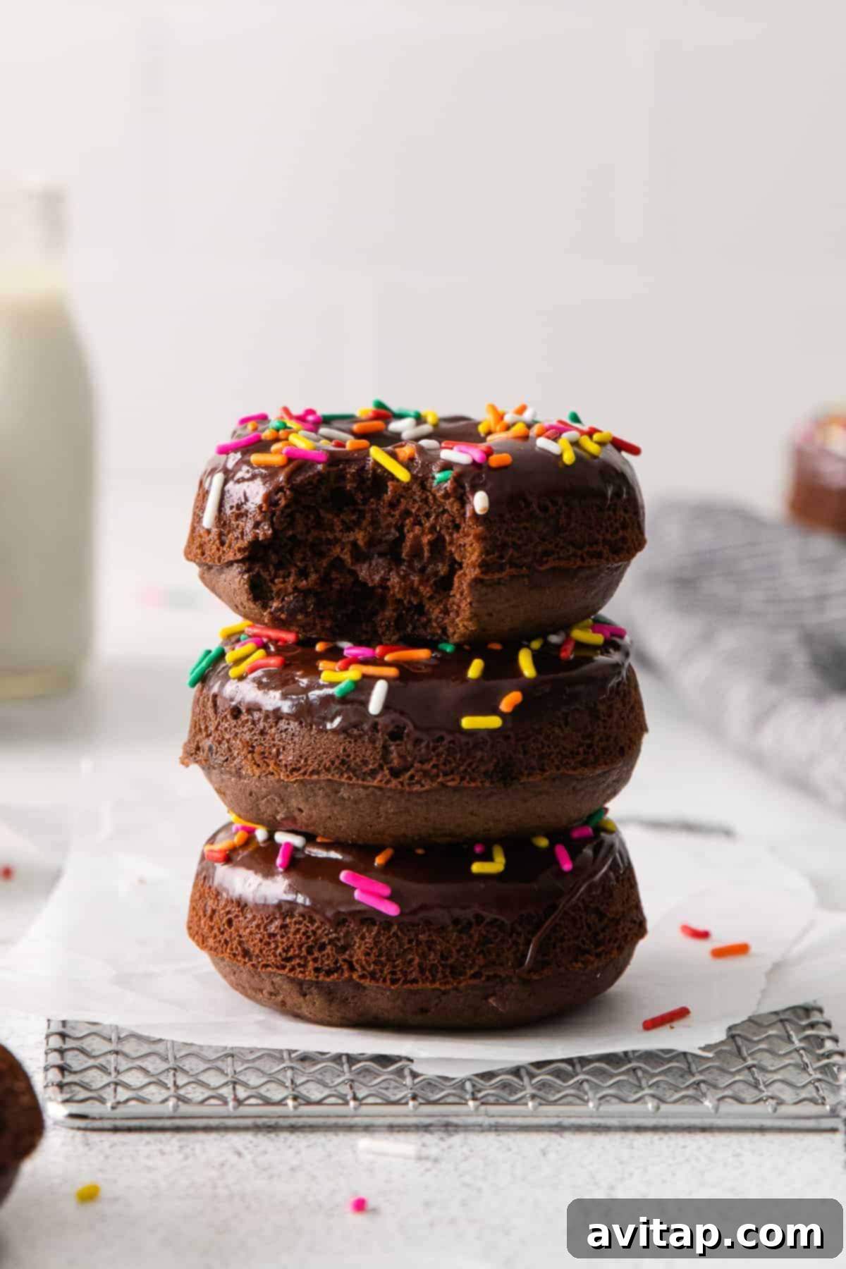 A beautifully stacked tower of glazed and sprinkled chocolate baked donuts.