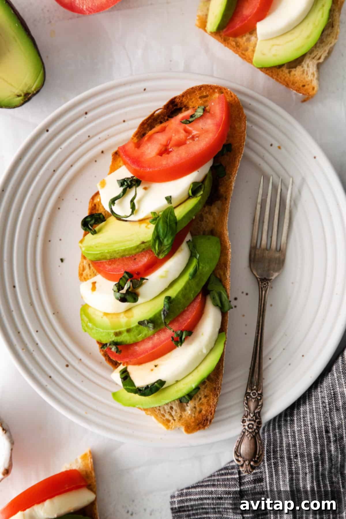 Caprese ingredients artfully arranged on avocado toast on a plate