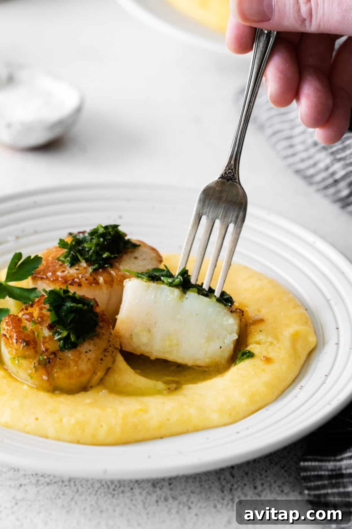 A fork taking a bite of scallops, showing the tender interior. 
