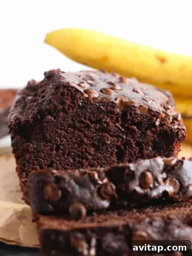 A close-up shot of a rich chocolate chip banana bread loaf, showcasing its moist texture and abundant chocolate chips.