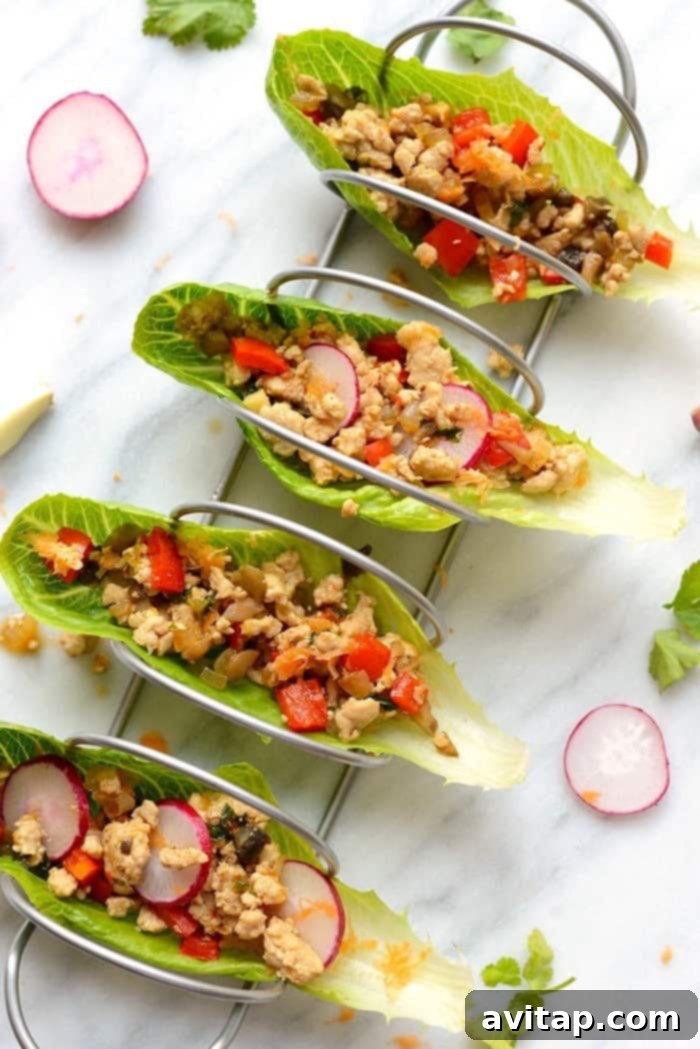 High-Protein, Low-Carb Thai Chicken Lettuce Wraps Top view of vibrant Thai Chicken Lettuce Wraps arranged in taco holders, garnished with fresh herbs and radishes.