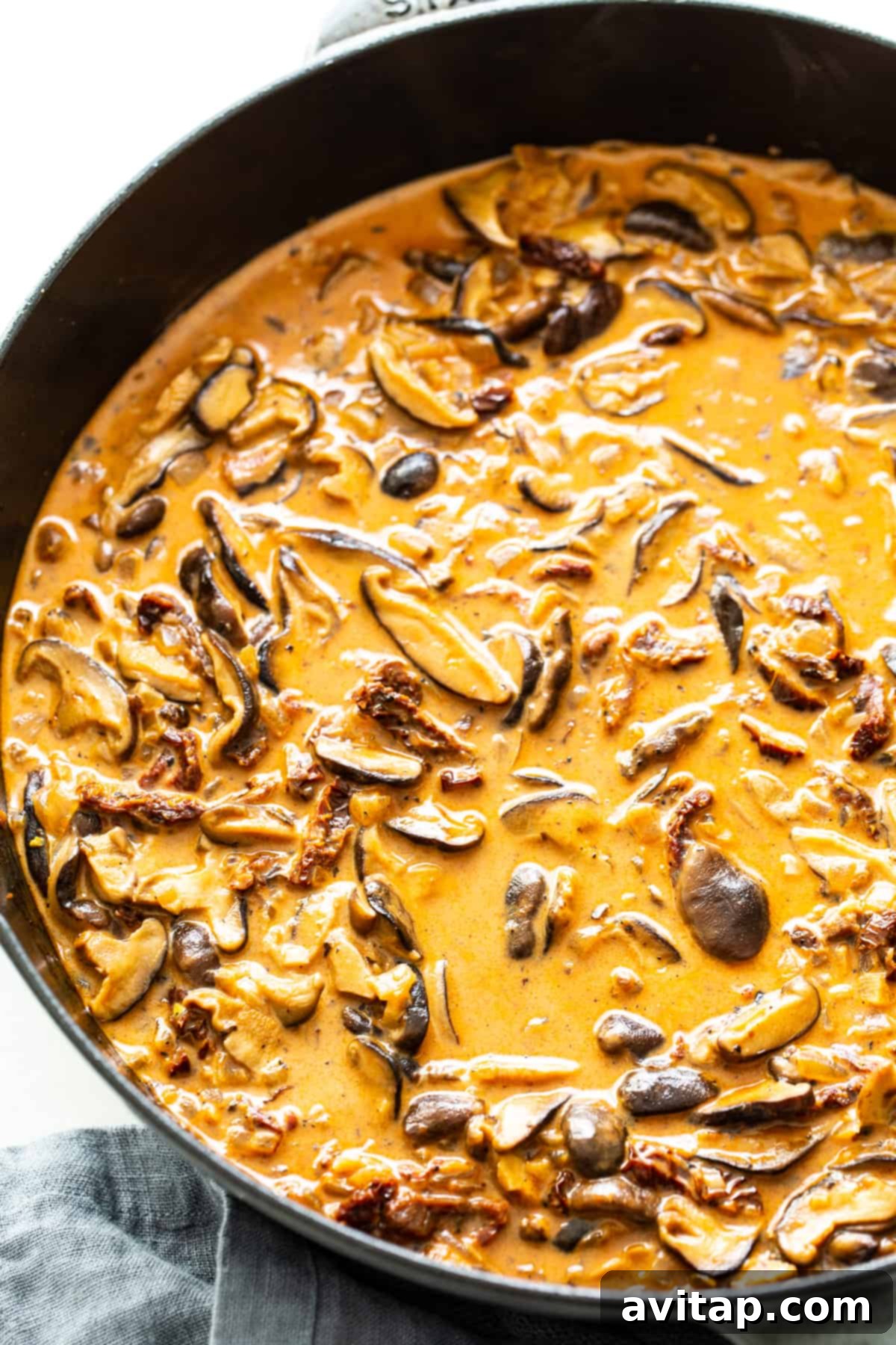 Creamy chicken mushroom pasta sauce simmering in a large pan