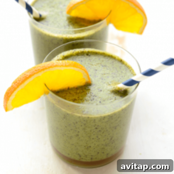 Two glasses of green smoothie with orange slices.