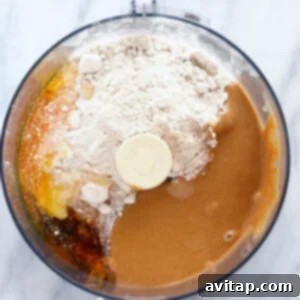 A food processor filled with ingredients for a peanut butter protein bar before blending.