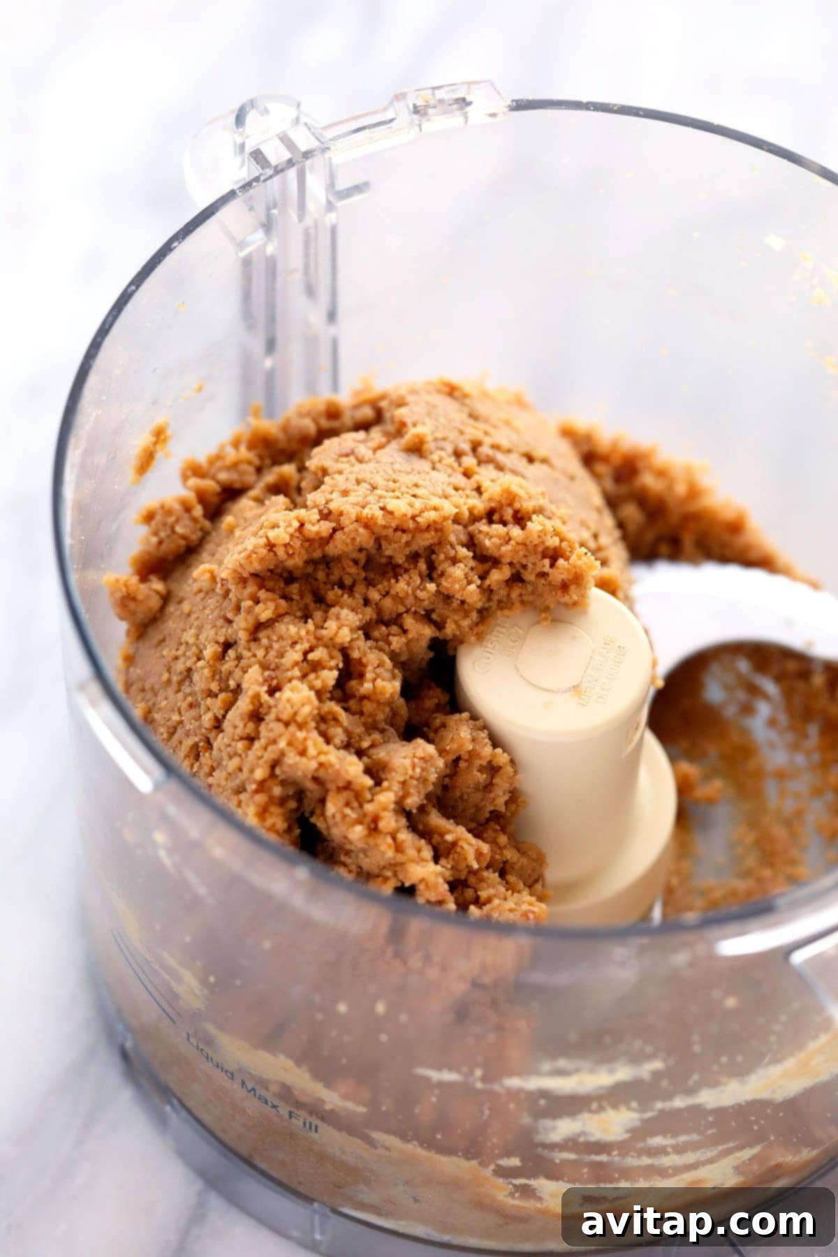 Smooth protein bar dough forming in a food processor, ready to be pressed into a pan.