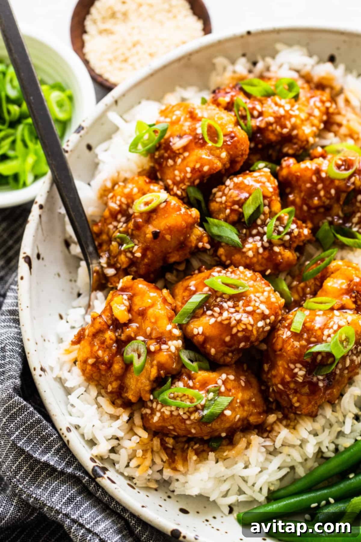 Air Fryer Honey Sesame Chicken in a serving bowl, garnished with sesame seeds and green onions.