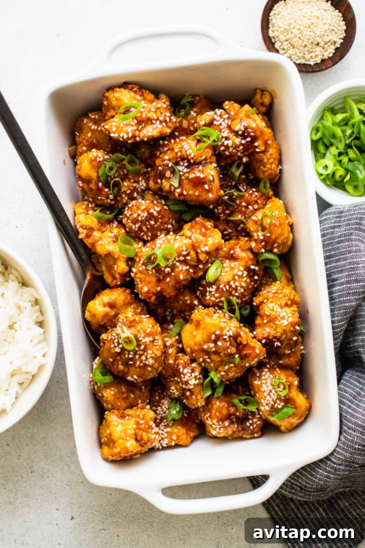 Finished honey sesame chicken in a serving dish, garnished with sesame seeds.