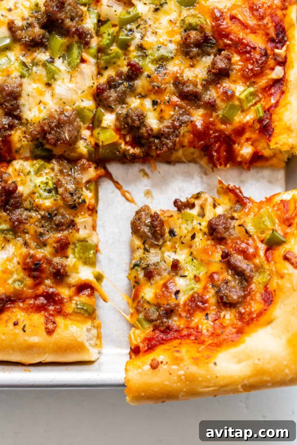 Grandma Marie's Homemade Sheet Pan Pizza Delicious slices of homemade sheet pan pizza topped with sausage, green peppers, and onions, served warm on a baking sheet.