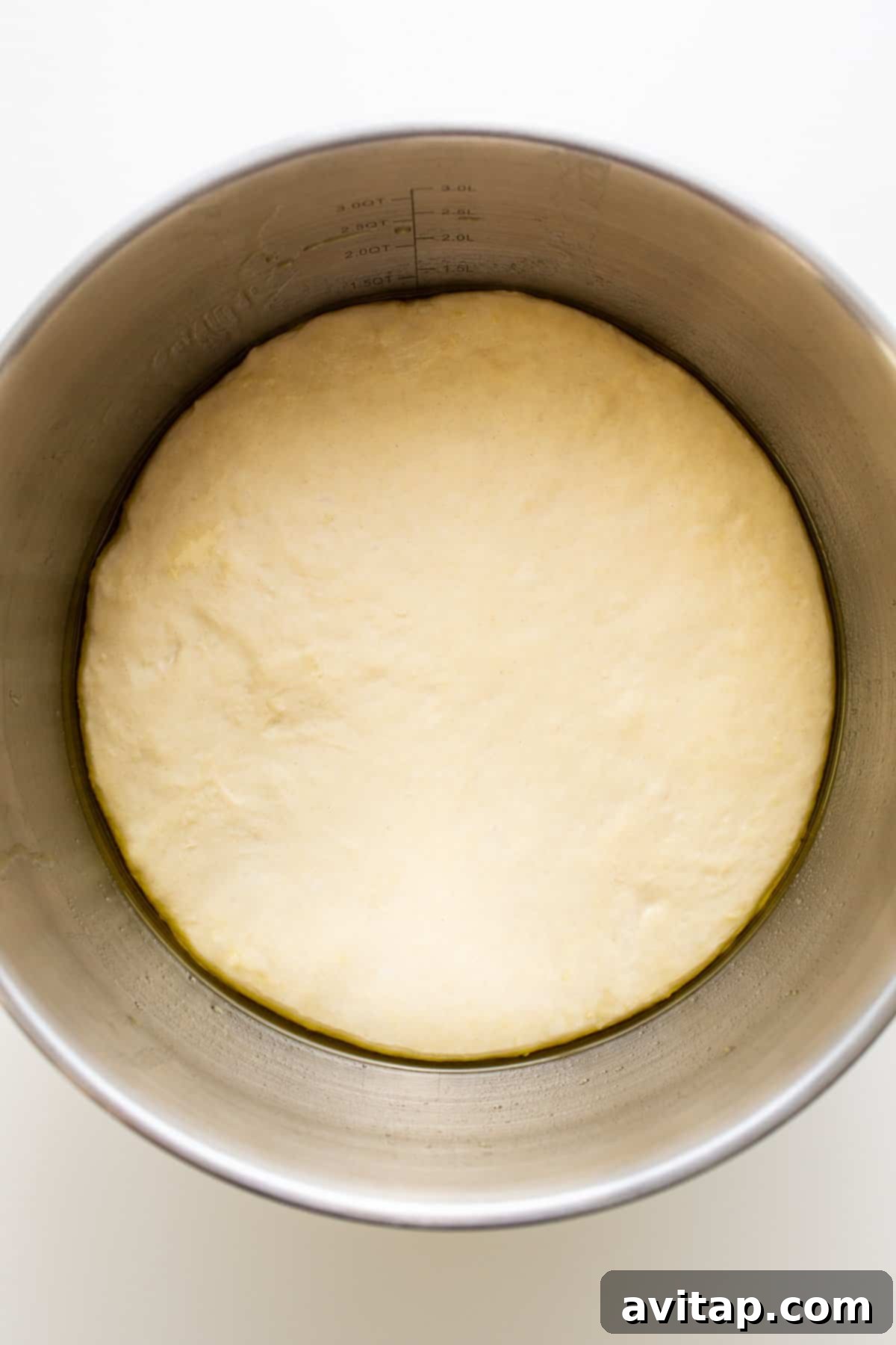 Pizza Dough Undergoing First Proof Pizza dough rising beautifully in a large, olive oil-coated bowl, covered with a tea towel, in a warm environment.