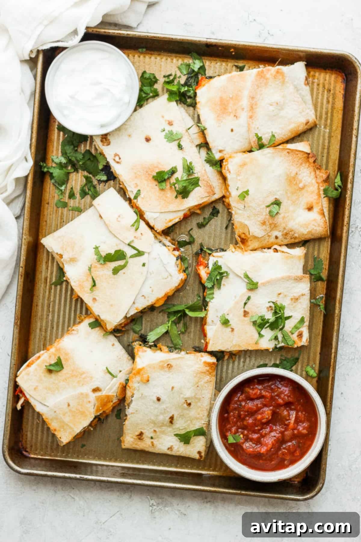 Crispy sheet pan quesadillas topped with fresh cilantro, ready to be served with sour cream and salsa.