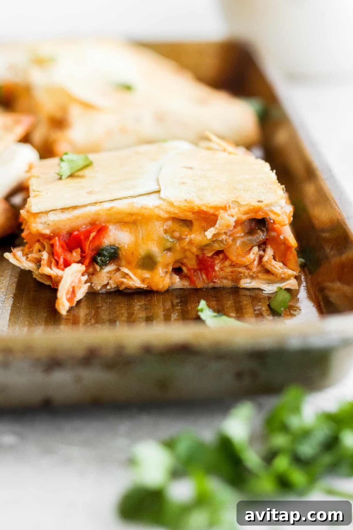 The savory filling of shredded chicken, vegetables, and melted cheese spread out on tortillas before folding.