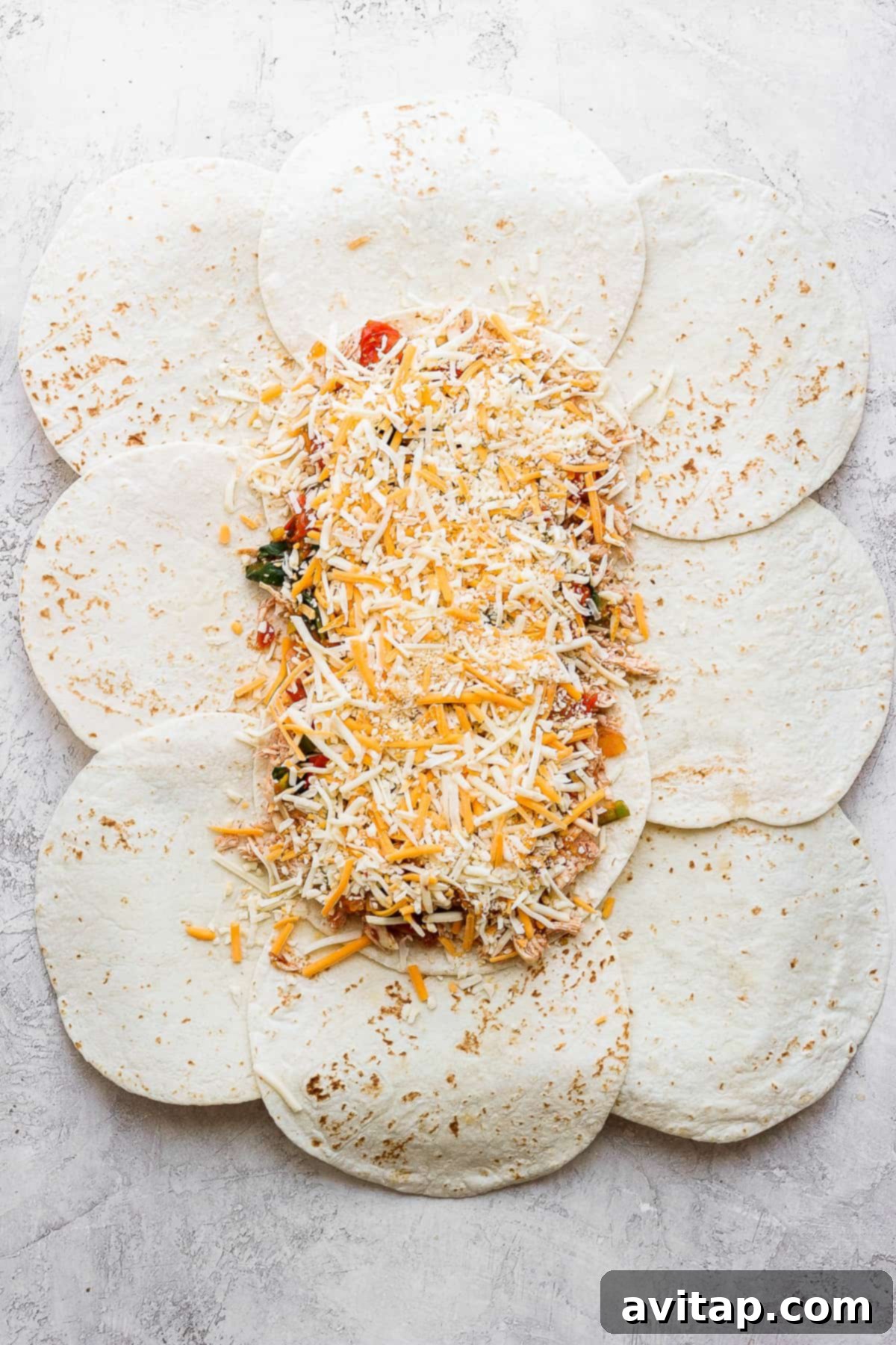 The layered filling for sheet pan quesadillas, showing shredded chicken, sautéed vegetables, and cheese spread over a base of tortillas.