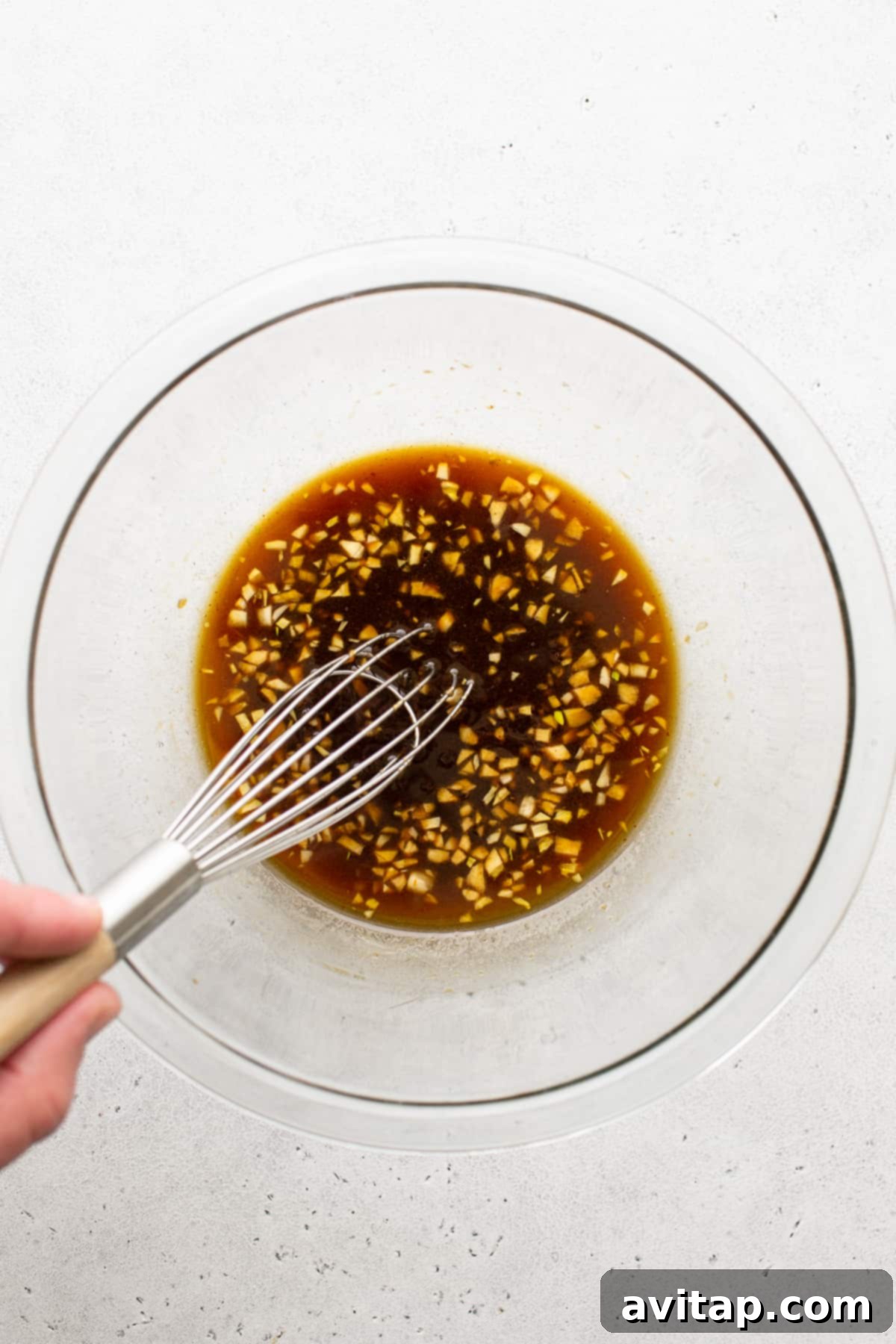 A bowl of rich, amber-colored chicken kabob marinade ready for use.