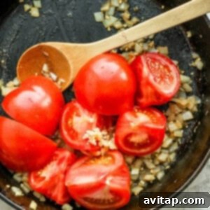 Quartered tomatoes, onions, and garlic sautéing in a pot.