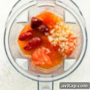 Tomatoes and onions being added to a blender for the sauce.