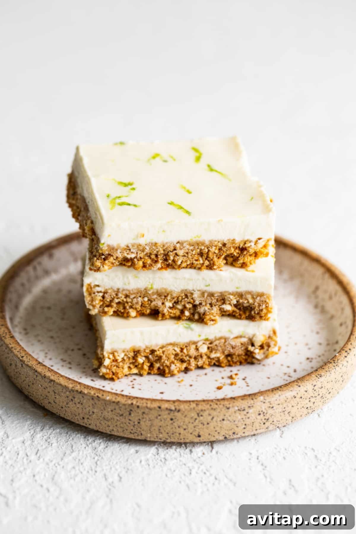 Stack of refreshing margarita pie bars with a pretzel crust and creamy lime topping, garnished with fresh lime zest.
