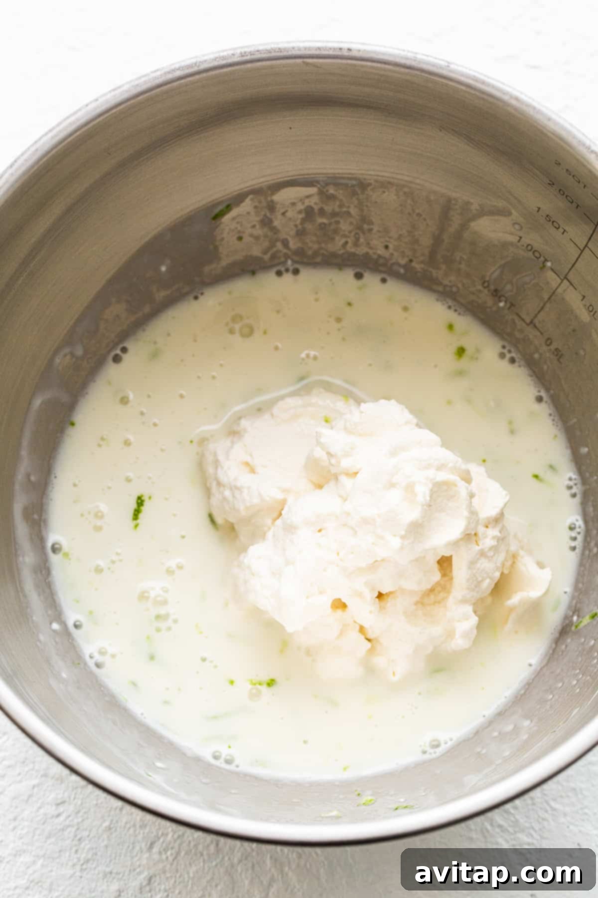 Close-up of the creamy, vibrant green margarita pie filling in a mixing bowl, ready to be spread over the crust.