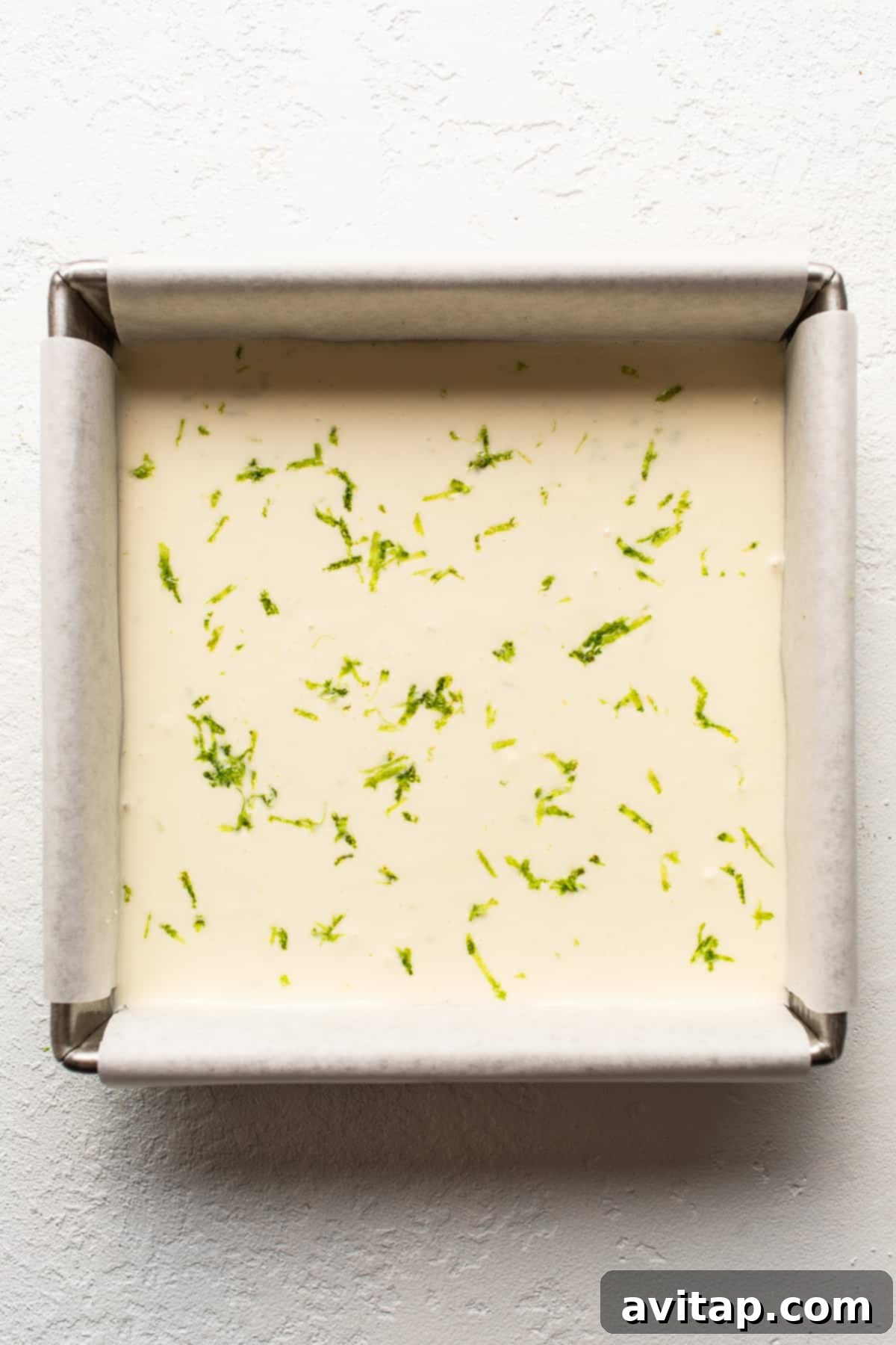 Margarita pie bars setting in a baking pan, showing the smooth top layer before freezing.