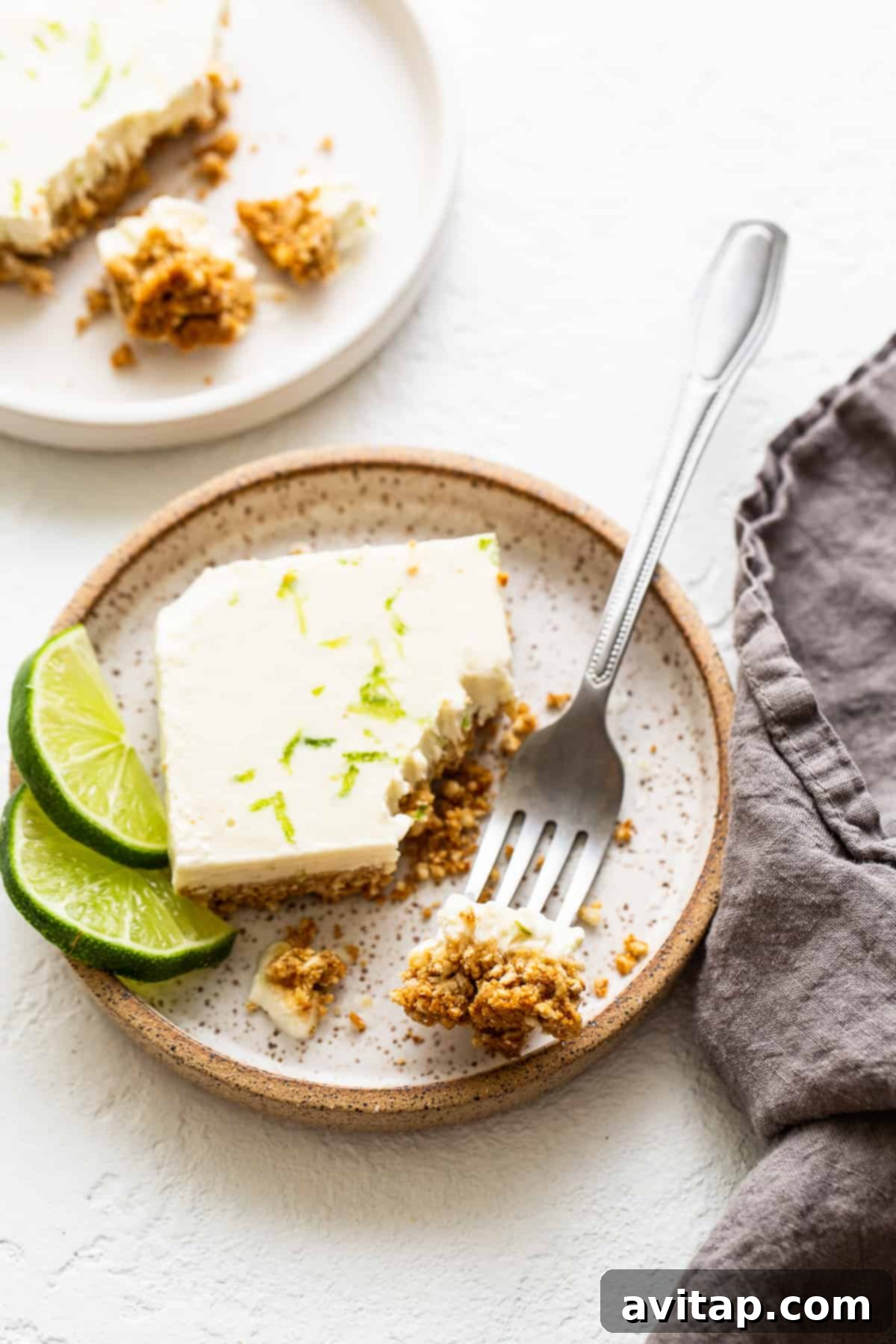 A single margarita pie bar on a plate with a fork, ready to be eaten.
