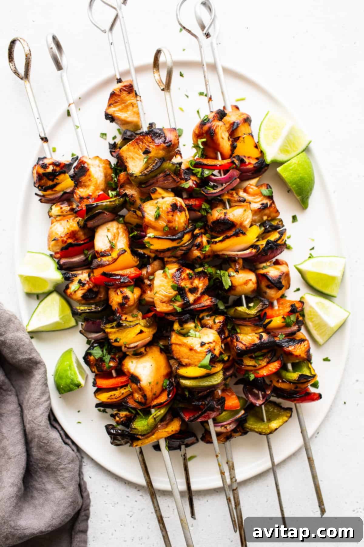 Beautifully arranged grilled chicken kabobs on a plate with fresh herbs.