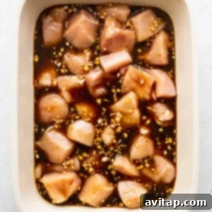 Chicken cubes marinating in a dish, absorbing flavors.