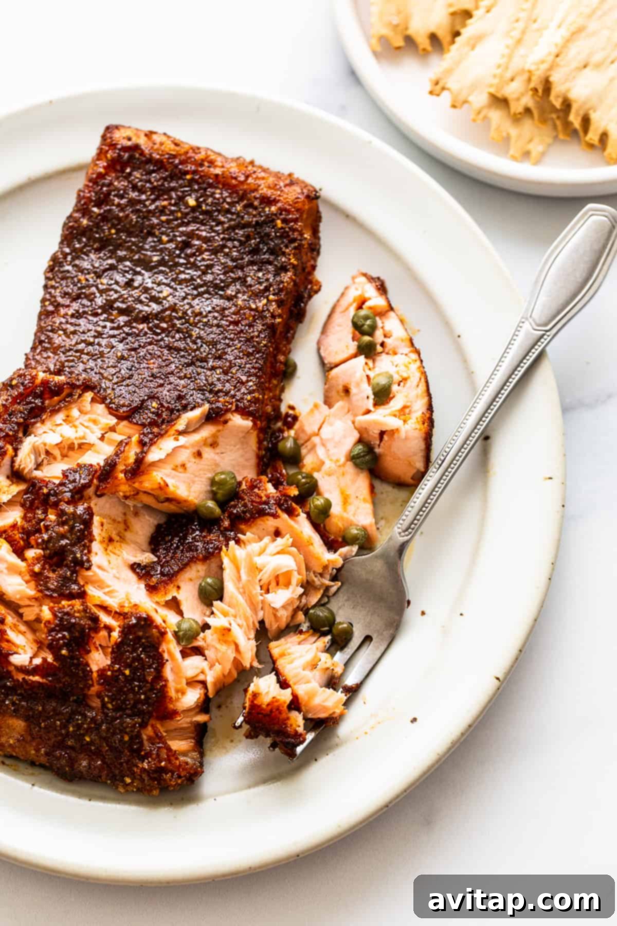 A fork gently separating tender, flaky pieces of smoked salmon on a plate, highlighting its perfect texture and doneness.