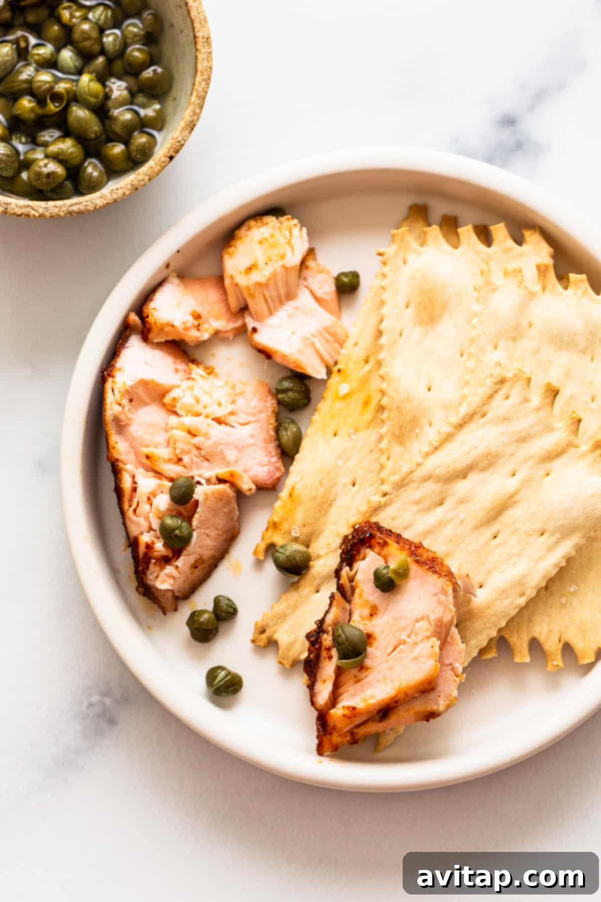 Crisp crackers topped with tender smoked salmon, adorned with briny capers, presented as an elegant and delicious appetizer.